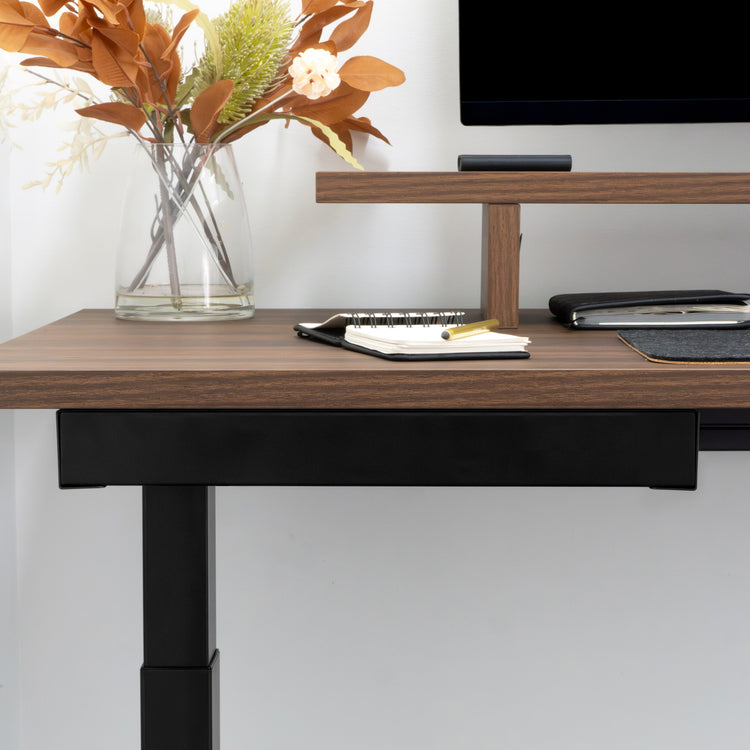 Black Desky Ultra Slim Under Desk Drawer mounted below a dark wood desk, with a monitor and vase.