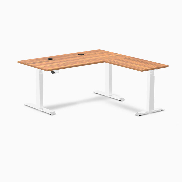 Desky L-Shape Laminate Sit Stand Desk in Prime Oak with white frame and grommets.
