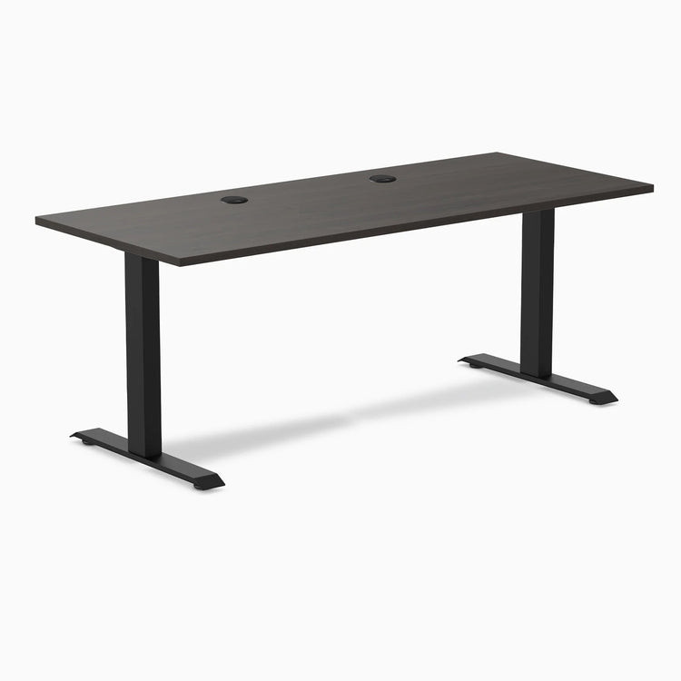 Desky Zero fixed-height office desk with burnished wood laminate top, two grommets, and matte black steel frame.