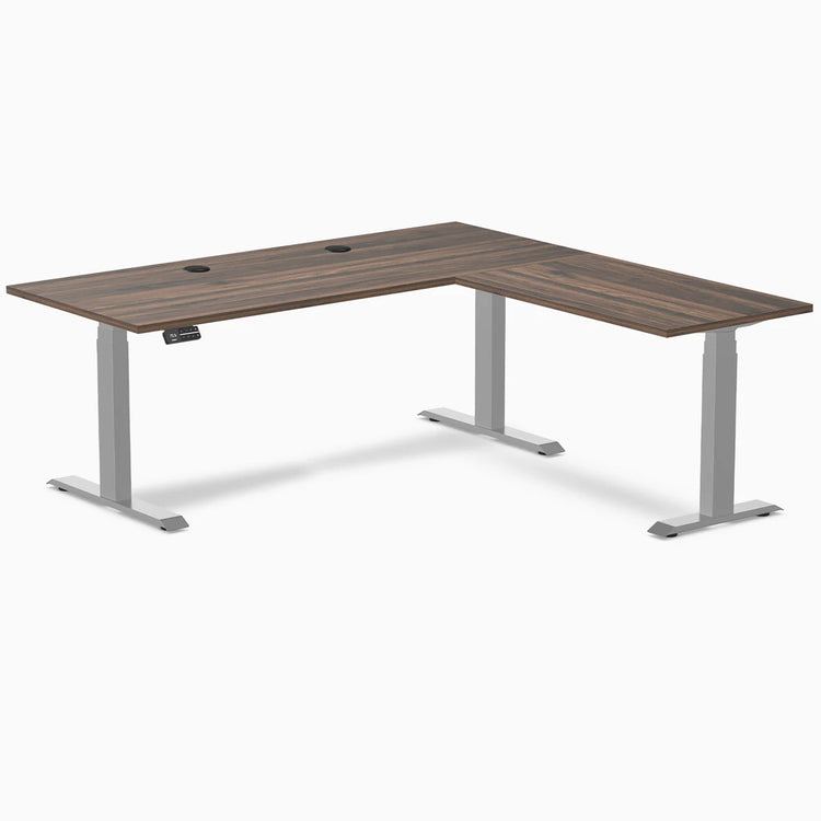 Desky L-Shape Laminate Sit Stand Desk with Jarrah Legno top, gray legs, and grommets.