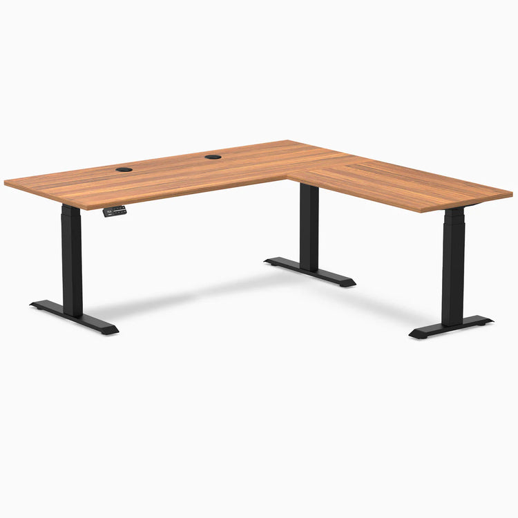 Prime Oak L-Shape Laminate Sit Stand Desk with matte black frame and grommets.