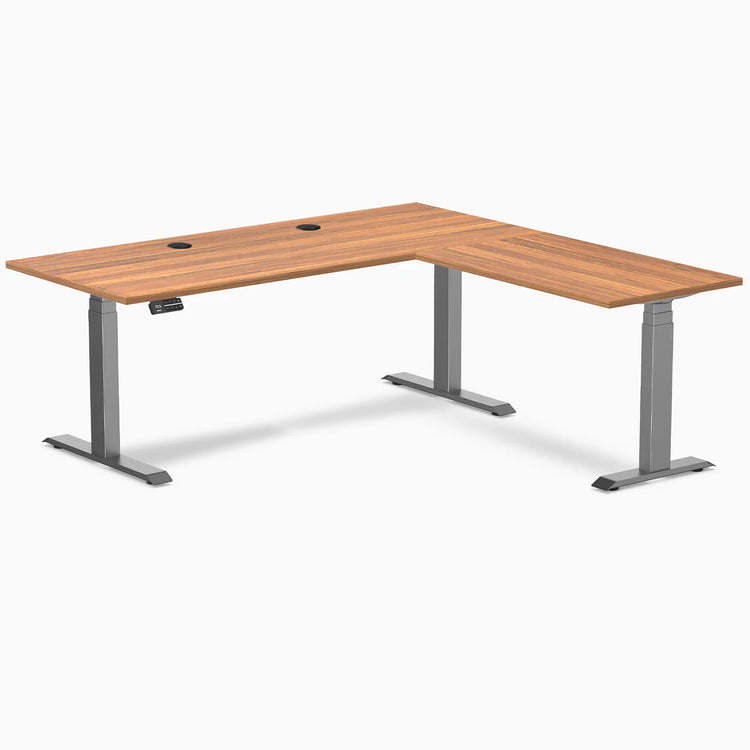 Prime Oak Desky L-Shape Laminate Sit Stand Desk with Space Gray frame and grommets.
