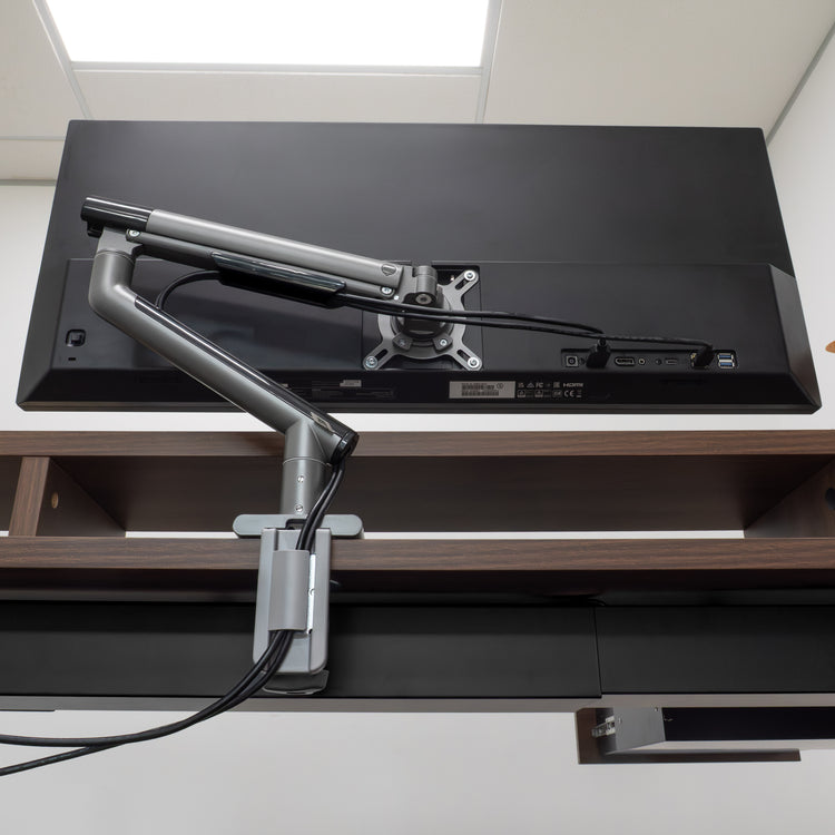 Desky Single Slim Aluminium Monitor Arm in space gray, mounted to a desk, supporting a black monitor.