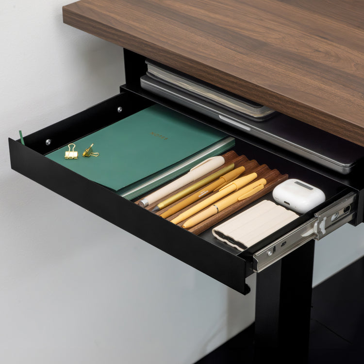 Black Desky Ultra Slim Under Desk Drawer, open and filled with pens, notebooks, and tech accessories.