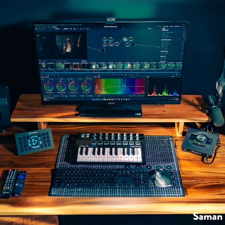Desky Minimal Monitor Stand in light brown wood, raising a large monitor above a keyboard, mouse, and audio equipment.