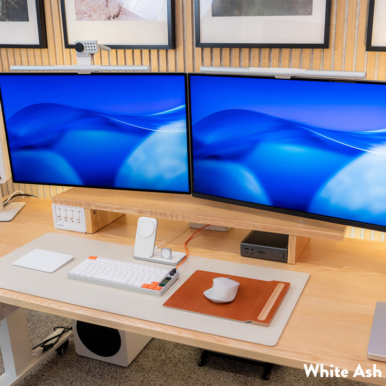 Desky Minimal Monitor Stand in White Ash melamine, supporting two monitors on a light wood desk.