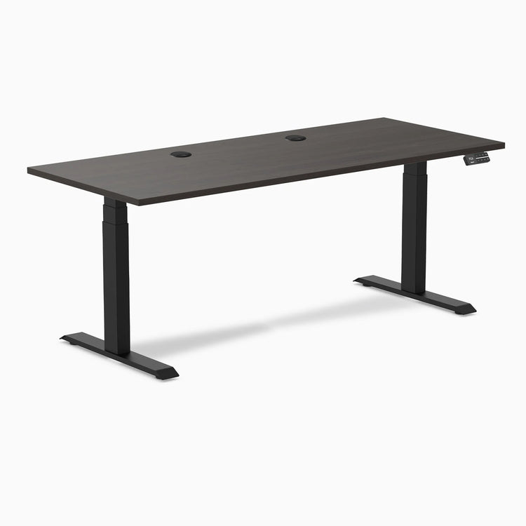 Desky Dual sit-stand desk with burnished wood laminate top, two grommets, and matte black frame.