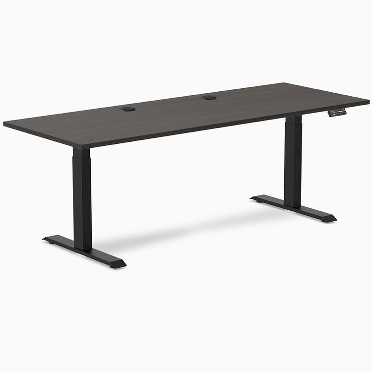 Desky Dual sit-stand desk with burnished wood laminate top, two grommets, and matte black frame.