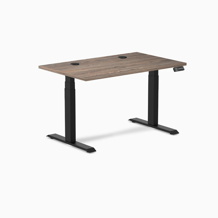 Desky Dual sit-stand desk with natural walnut laminate top, two grommets, and matte black legs.