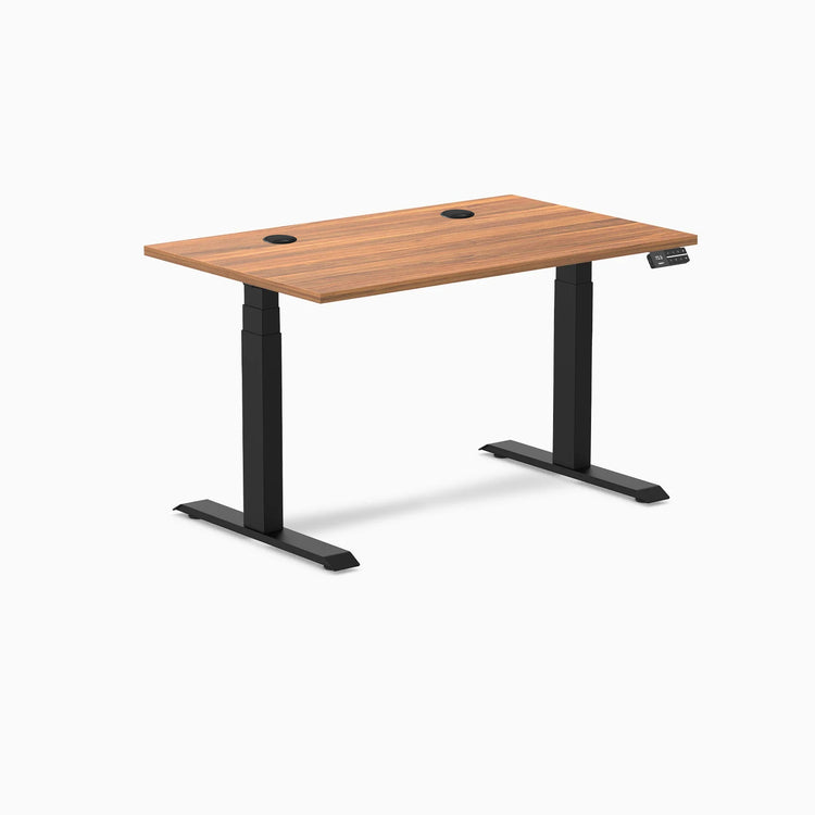 Desky Dual sit-stand desk with Prime Oak laminate top, two grommets, and matte black frame.
