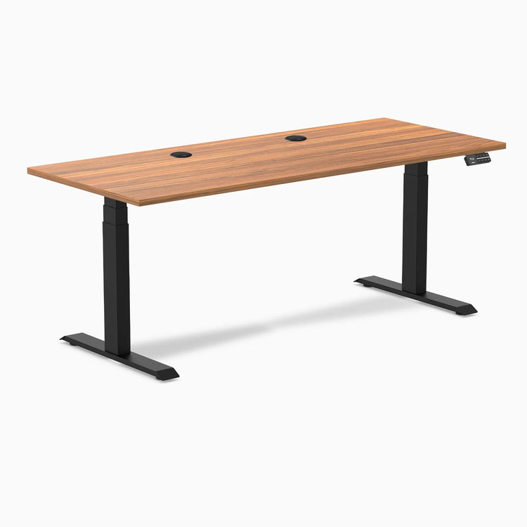 Desky Dual sit-stand desk with Prime Oak laminate top, two grommets, and matte black frame.