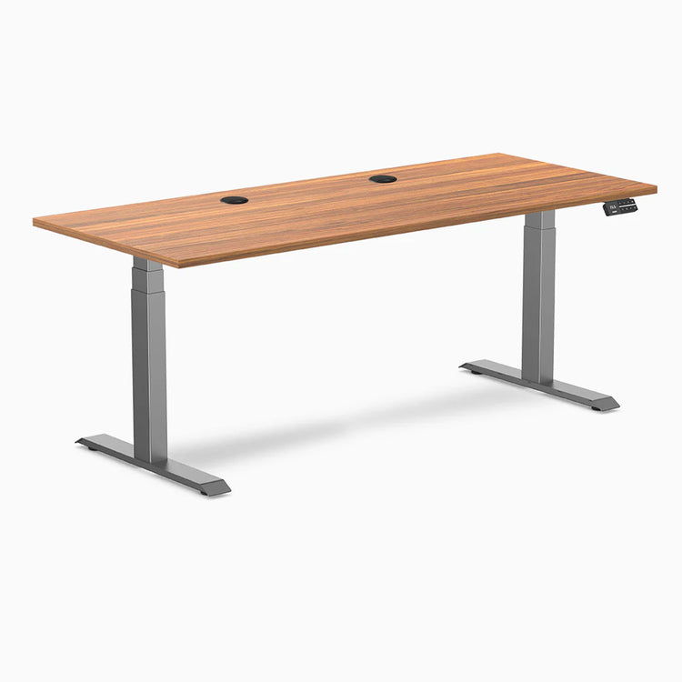 Desky Dual sit-stand desk with Prime Oak laminate top, two grommets, and Space Gray frame.