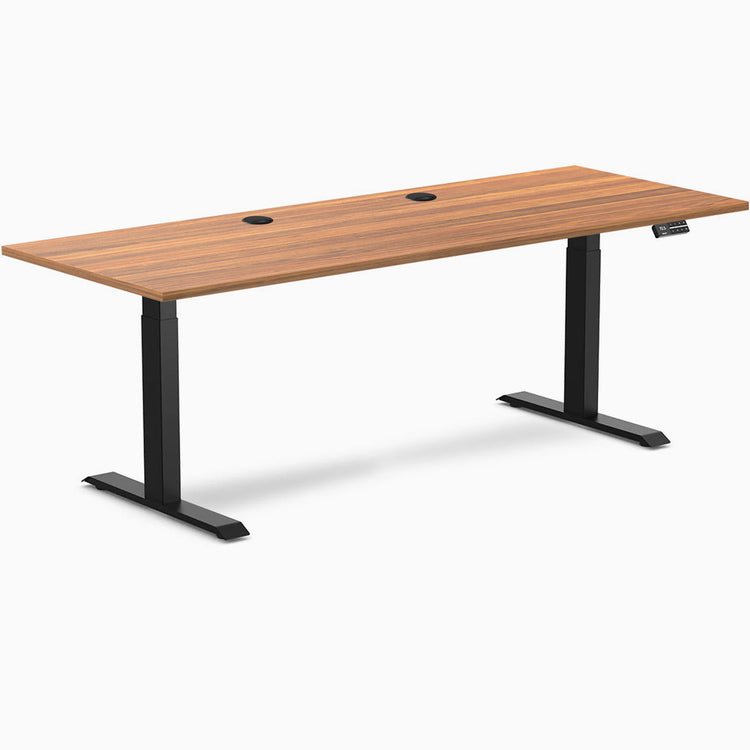 Prime Oak Desky Dual Laminate Sit Stand Desk, 78.7x29.5 inches, with two grommets and matte black frame.