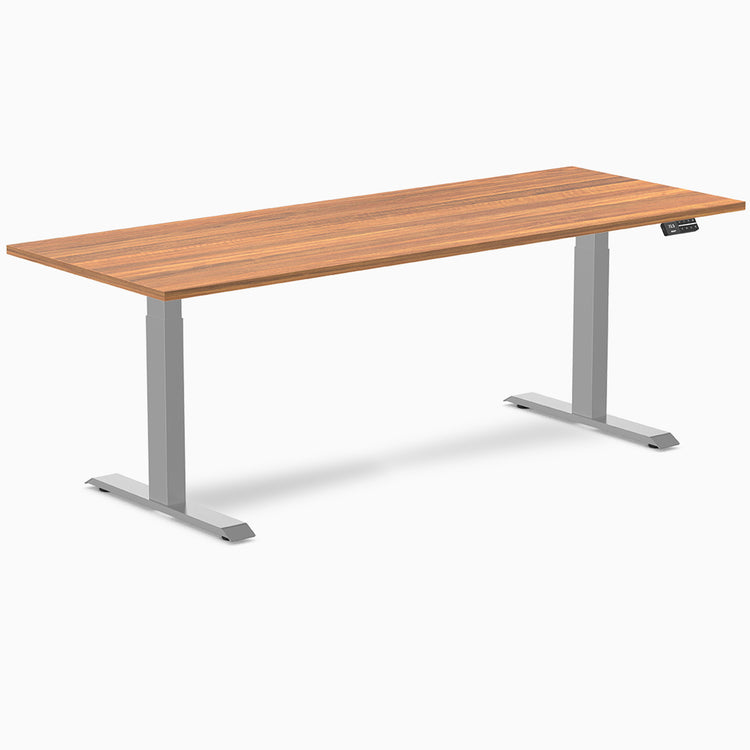 Desky Dual Laminate Sit Stand Desk with a warm brown woodgrain top and silver adjustable legs.