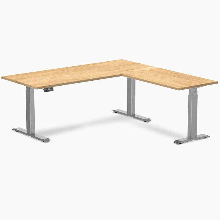 White Oak L-Shape sit-stand desk with a natural hardwood top and space gray adjustable legs.