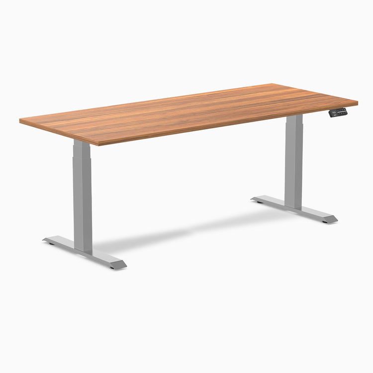 Desky Dual Laminate Sit Stand Desk with a warm brown wood-grain top and silver adjustable legs.