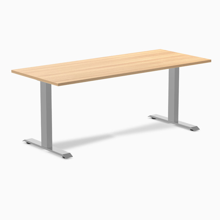 Desky Zero fixed height office desk with light wood laminate top and silver steel frame.