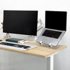 Silver laptop on a white Desky Universal Laptop Mount next to a monitor, both on a desk.