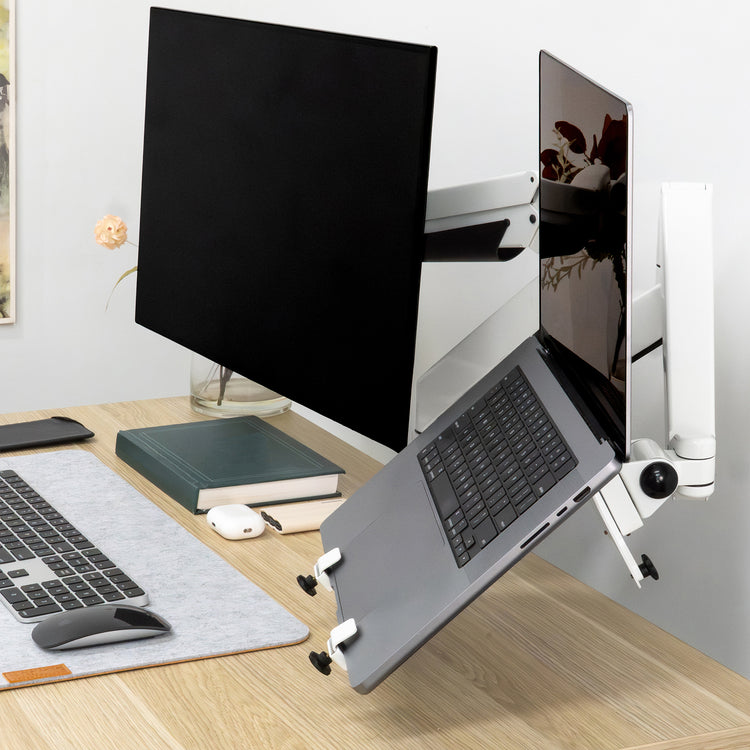 White Desky Universal Laptop Mount holding a silver laptop next to a black monitor on a light wood desk.