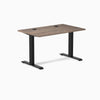 Desky Zero fixed height office desk with natural walnut laminate top, matte black steel frame, and grommets.