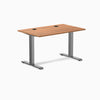 Desky Zero fixed height office desk with Prime Oak laminate top, grommets, and Space Gray steel frame.