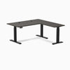 Desky L-Shape Laminate Sit Stand Desk in burnished wood with matte black legs and grommets.