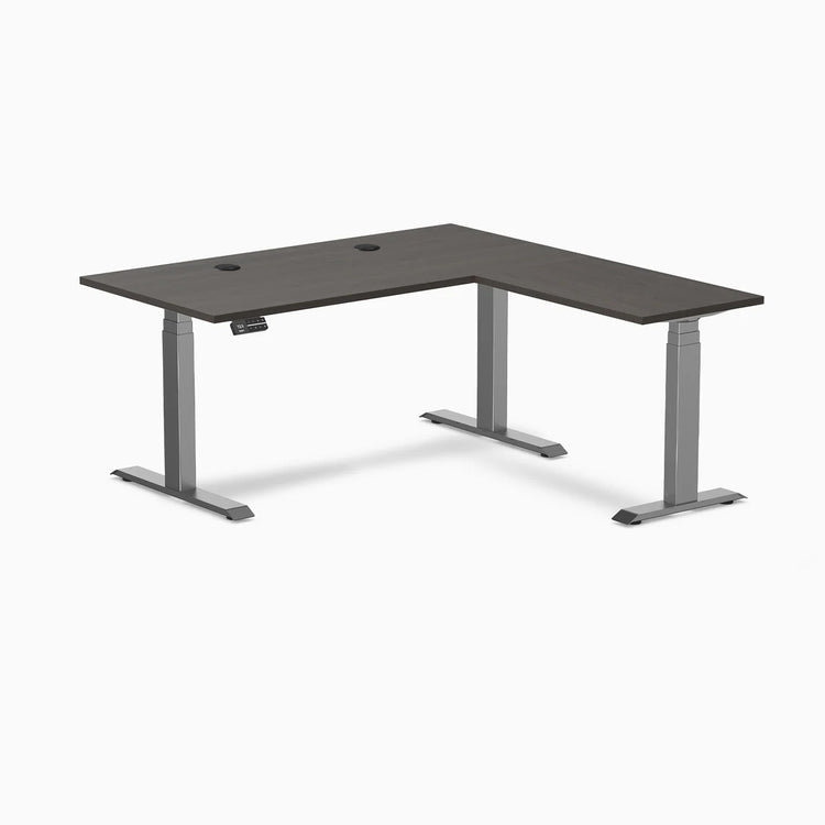 Desky L-Shape Laminate Sit Stand Desk in burnished wood with space gray frame and grommets.