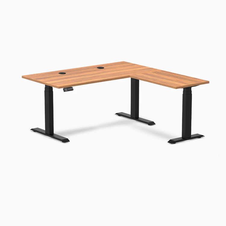 Prime Oak laminate L-shaped sit-stand desk with matte black frame, grommets, and control panel.