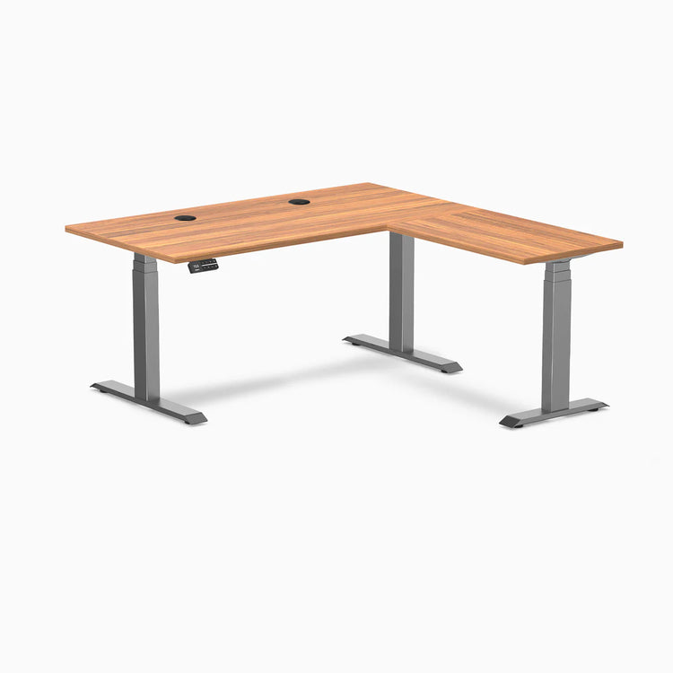 Desky L-Shape Laminate Sit Stand Desk in Prime Oak with Space Gray frame and grommets.