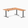 Desky L-Shape Laminate Sit Stand Desk in Prime Oak with Space Gray frame and grommets.