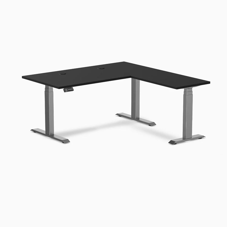 Desky L-Shape Laminate Sit Stand Desk in black with space gray frame and grommets.
