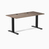 Desky Zero fixed height office desk with natural walnut laminate top, two grommets, and matte black steel frame.