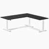 Black laminate L-shape sit-stand desk with white adjustable legs and grommets.
