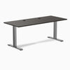 Desky Zero fixed height office desk with burnished wood laminate top, grommets, and space gray steel frame.