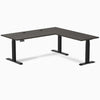 Burnished Wood L-shape laminate sit-stand desk with matte black legs and grommets.