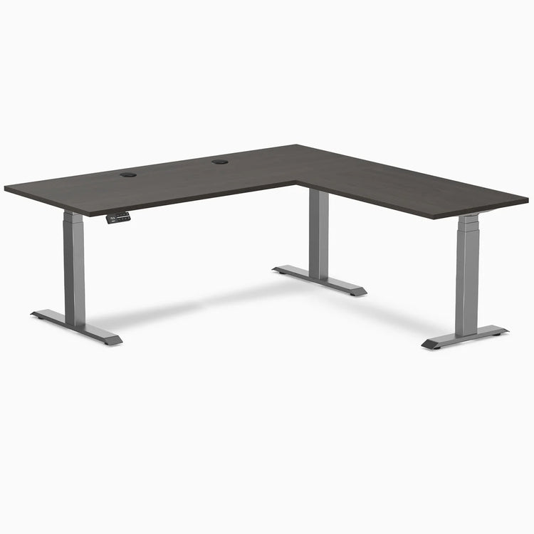 Desky L-Shape Laminate Sit Stand Desk in Burnished Wood with Space Gray frame and grommets.