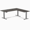 Desky L-Shape Laminate Sit Stand Desk in Burnished Wood with Space Gray frame and grommets.