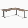 Desky L-Shape Laminate Sit Stand Desk in Natural Walnut with Space Gray frame and grommets.