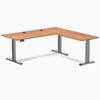 Prime Oak Desky L-Shape Laminate Sit Stand Desk with Space Gray frame and grommets.