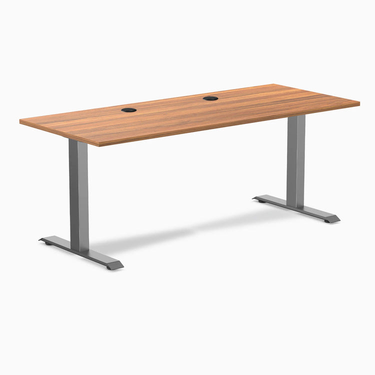 Desky Zero fixed height office desk with Prime Oak laminate top, two grommets, and Space Gray steel frame.