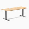 Desky Zero fixed height office desk with a Sublime Teak laminate top, Space Gray steel frame, and grommets.