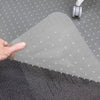 Hand lifting a corner of a translucent Desky Chair Mat with studded underside on gray carpet.