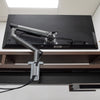 Desky Single Slim Aluminium Monitor Arm in space gray, mounted to a desk, supporting a black monitor.