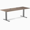 Desky Zero fixed-height office desk with natural walnut laminate top, grommets, and space gray steel frame.