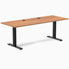 Desky Zero fixed height office desk with Prime Oak laminate top, black steel frame, and grommets.