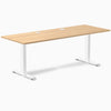 Desky Zero fixed height office desk with a Sublime Teak laminate top, white steel frame, and two grommets.