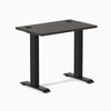 Desky Zero Mini sit-stand desk with burnished wood top, matte black legs, and grommets.