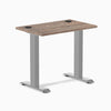 Desky Zero Mini desk with natural walnut top, gray fixed-height legs, and two grommets.