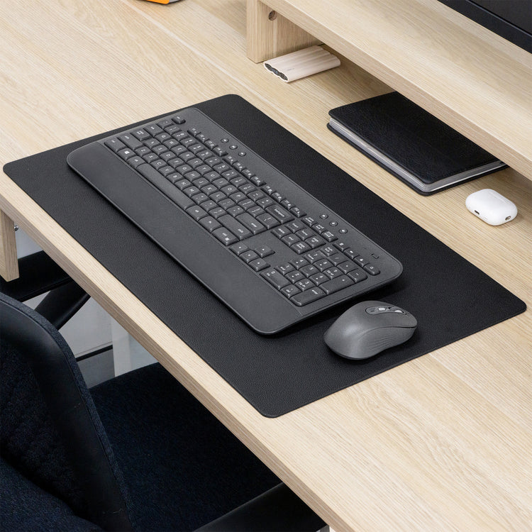 Black Desky leather desk mat on a light wood desk, with a keyboard and mouse.