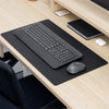 Black Desky leather desk mat on a light wood desk, with a keyboard and mouse.